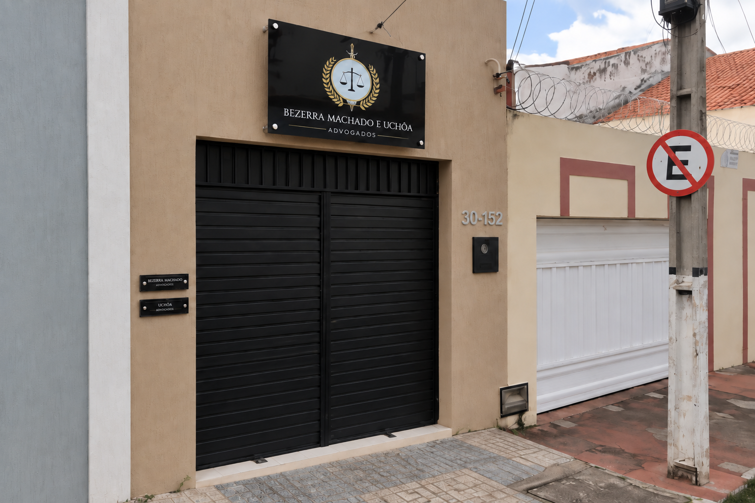 Vista lateral da fachada do escritório, com emblema da justiça na placa